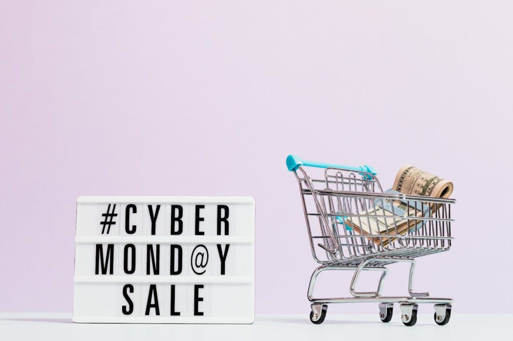 Shopping cart filled with cash beside a Cyber Monday sale sign, perfect for retail promotions.
